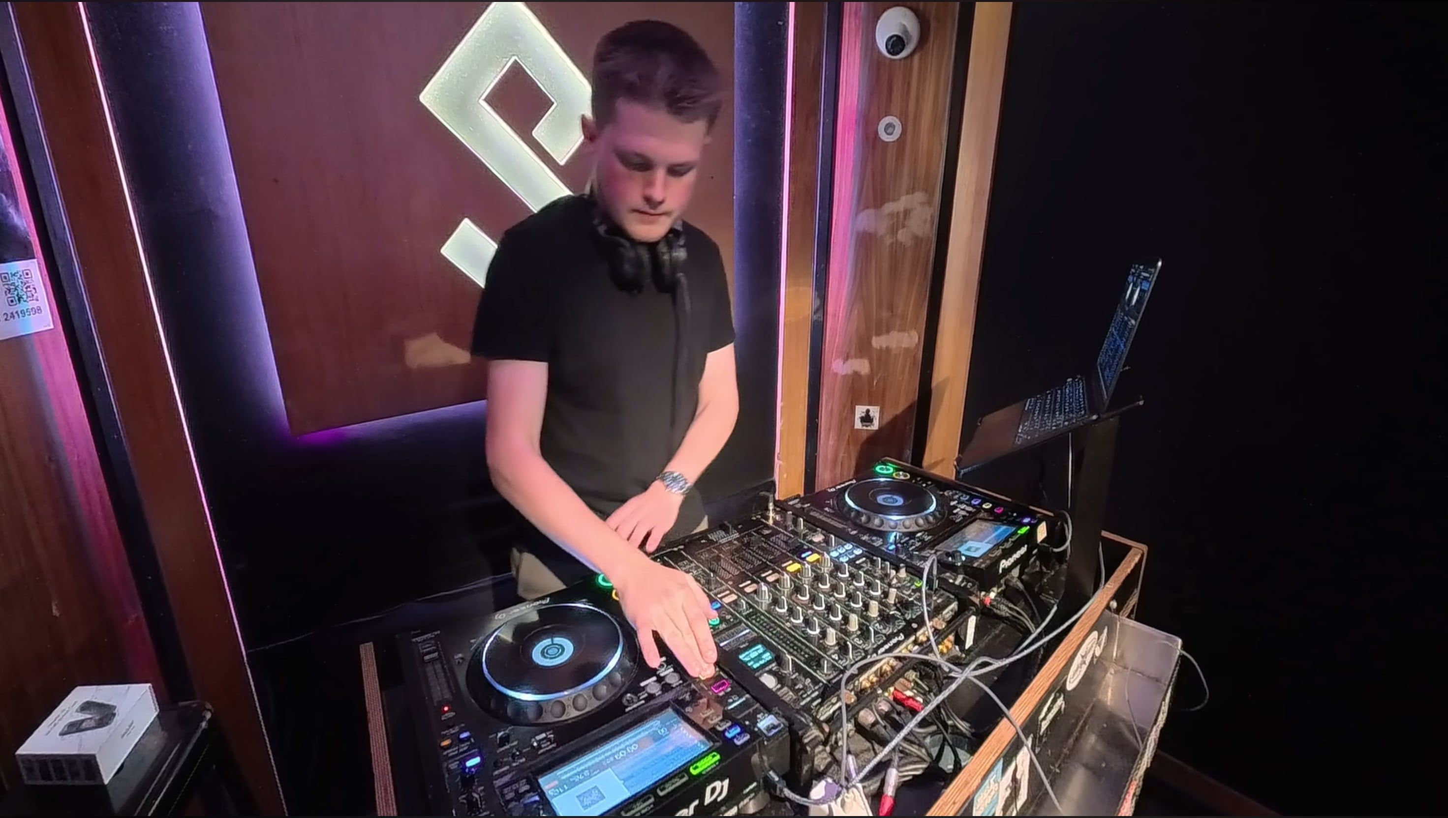 George mixing on club decks in a DJ booth